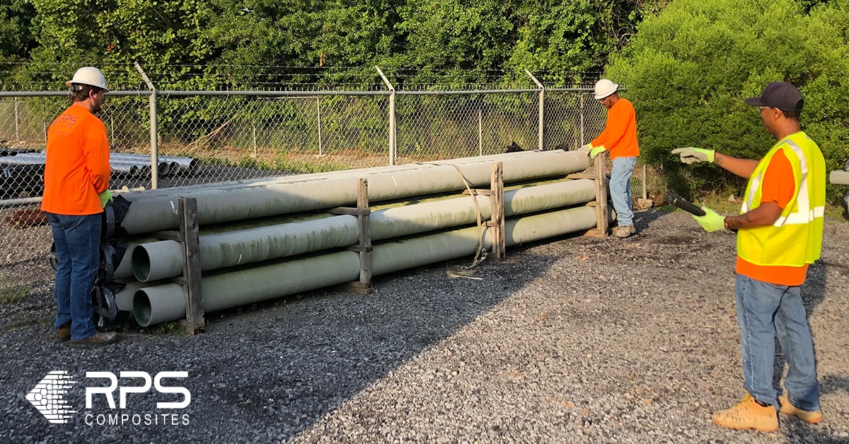 Two men prepare to lift a long piece of FRP pipe.